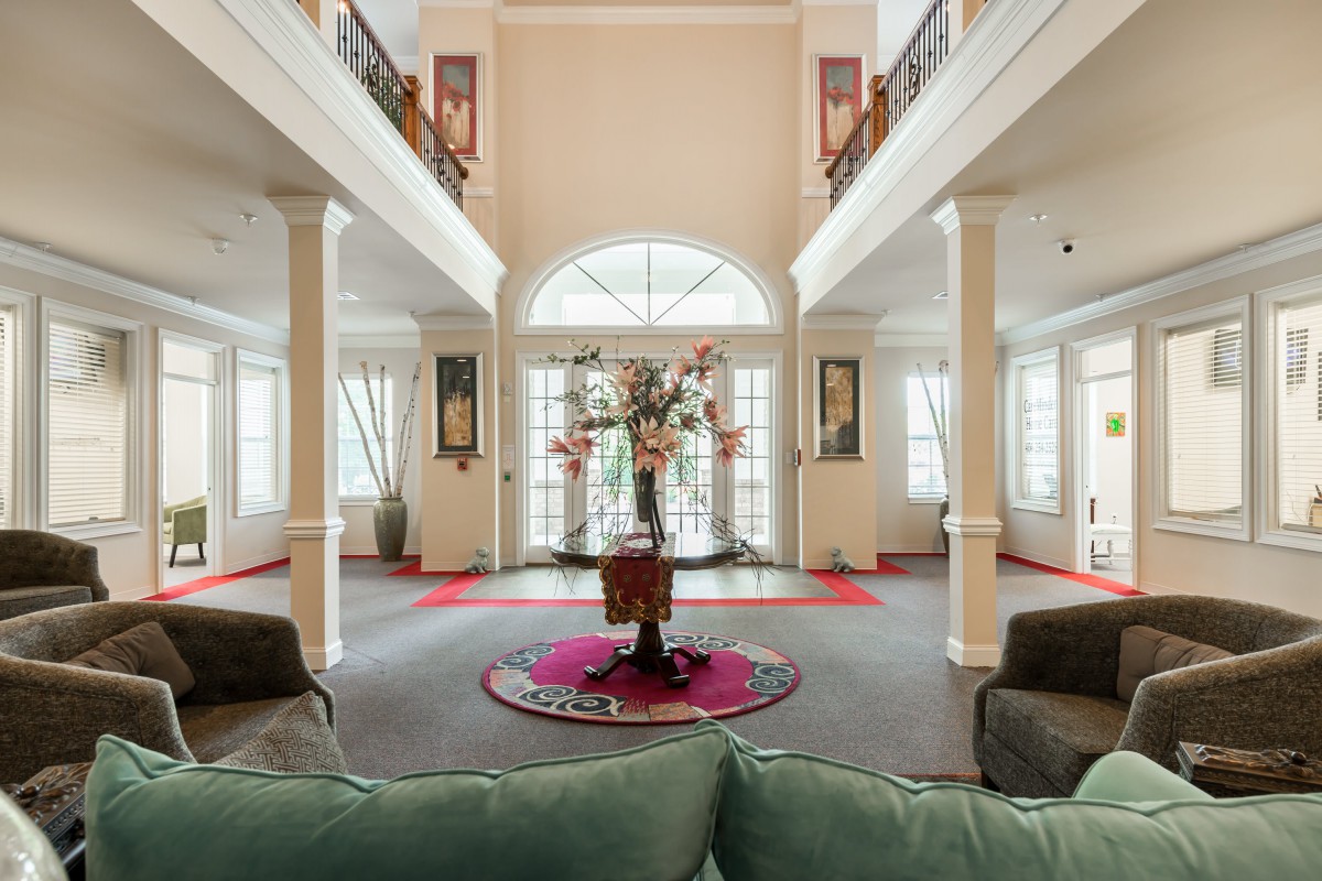A spacious and elegantly decorated living room with large windows, arches, and pillars.