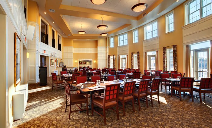 Elegant dining area with tables and chairs arranged in a spacious restaurant setting.