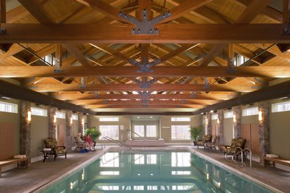 A luxurious indoor swimming pool featuring a wooden beam ceiling and elegant interior design.