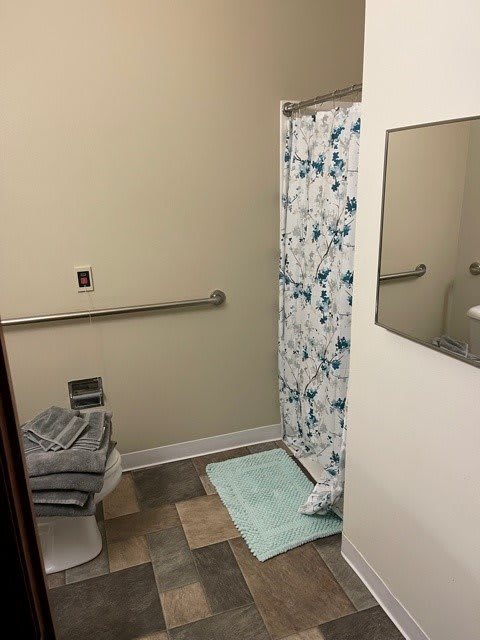 A bathroom with a shower, towels, and a safety grab bar.