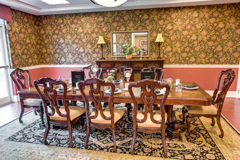A traditional dining room with elegant wooden furniture and ornate wallpaper.