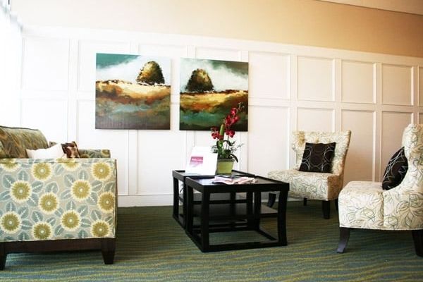 A cozy living room with modern decor, featuring two large pieces of artwork, a central table, and comfortable seating.