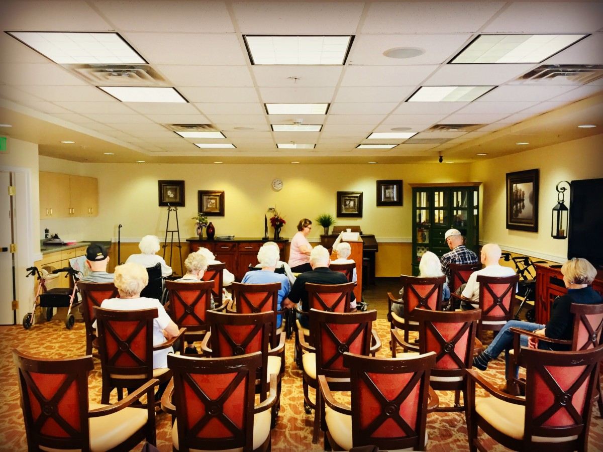 A group of elderly individuals seated in a meeting room for a presentation.