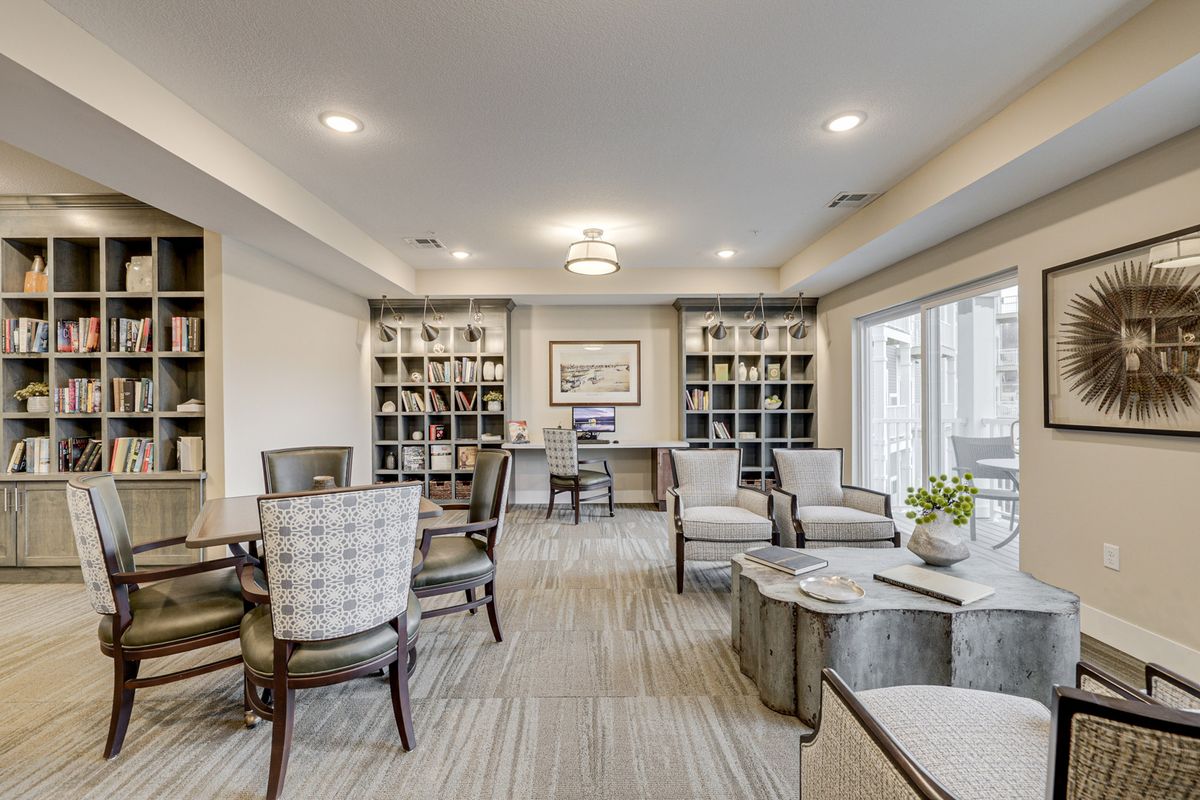 A modern living room with comfortable seating, shelves filled with decor, and large windows letting in natural light.