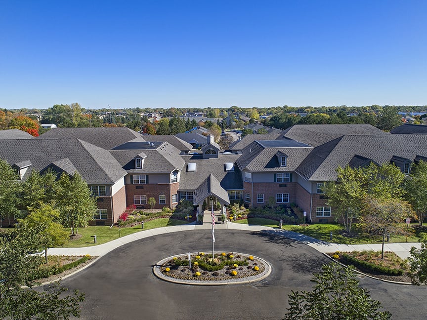 Aerial view of a residential building complex with landscaped surroundings and a circular driveway.