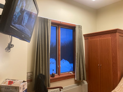 A cozy room featuring a television, warm wood tones, and a window revealing a serene winter scene.