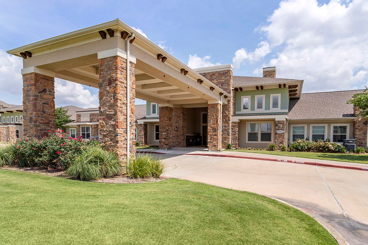 A modern residential building with a stone facade and landscaped entrance.