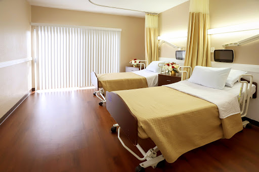 A modern hospital patient room featuring two beds with warm decor.