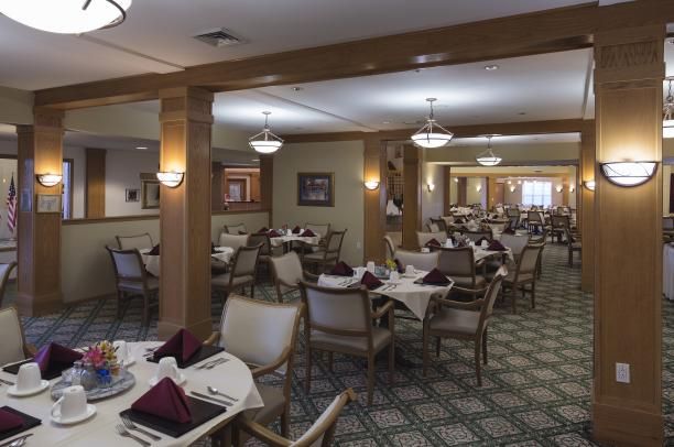 An elegant dining area with neatly arranged tables and chairs, featuring warm lighting.