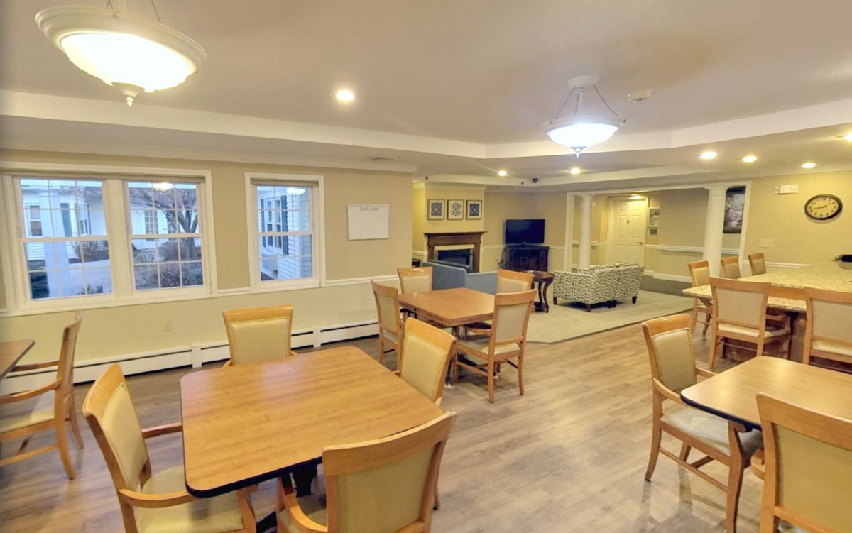 A cozy communal space with dining tables and a living area, featuring a fireplace and television.