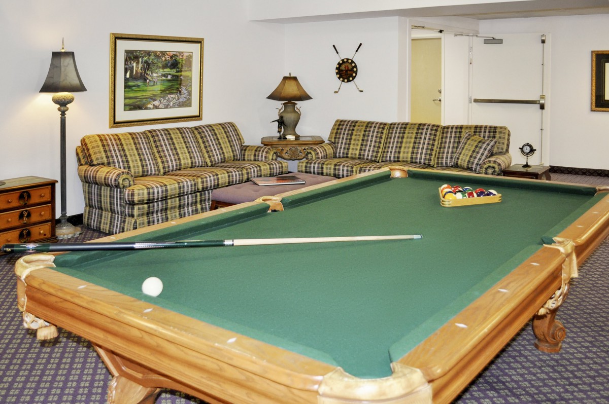 A cozy recreation room featuring a pool table and comfortable plaid couches.