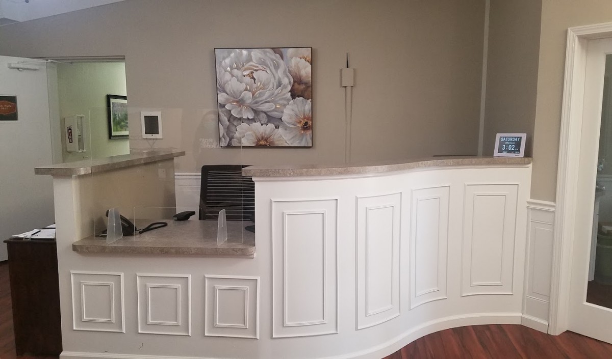 A modern reception desk area with elegant paneling and wall art.