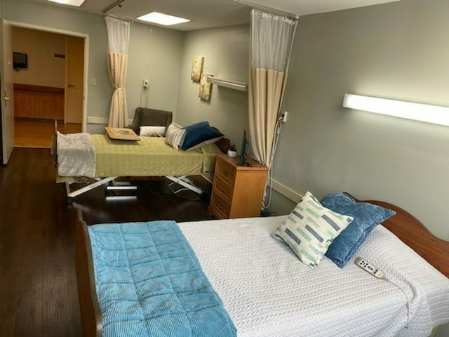 A hospital room with two patient beds separated by privacy curtains.