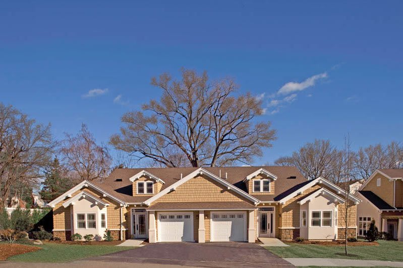 A suburban townhouse or duplex with a shared driveway and garages.