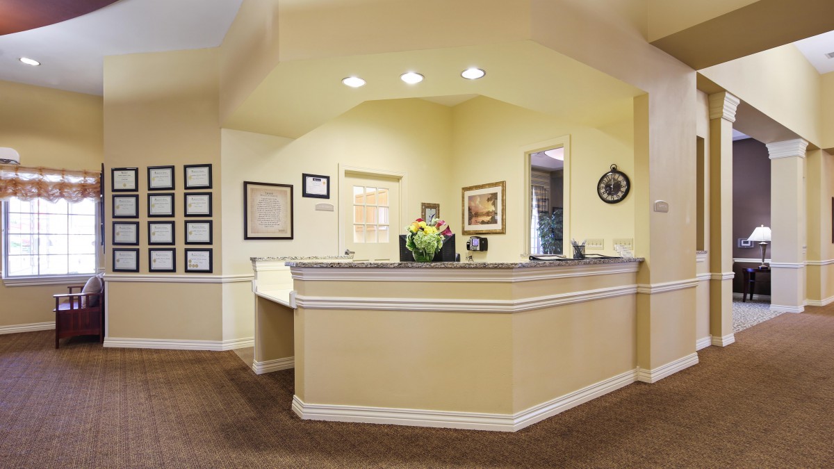 A welcoming reception area with a desk, flowers, and framed pictures on the walls.