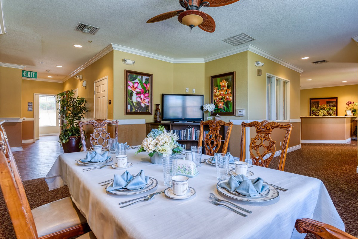 A beautifully set dining table with elegant tableware and floral centerpiece in a well-decorated room.