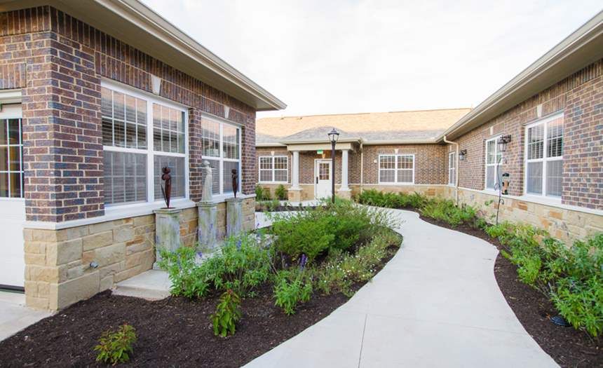 A brick building with a landscaped garden and a curved concrete pathway.
