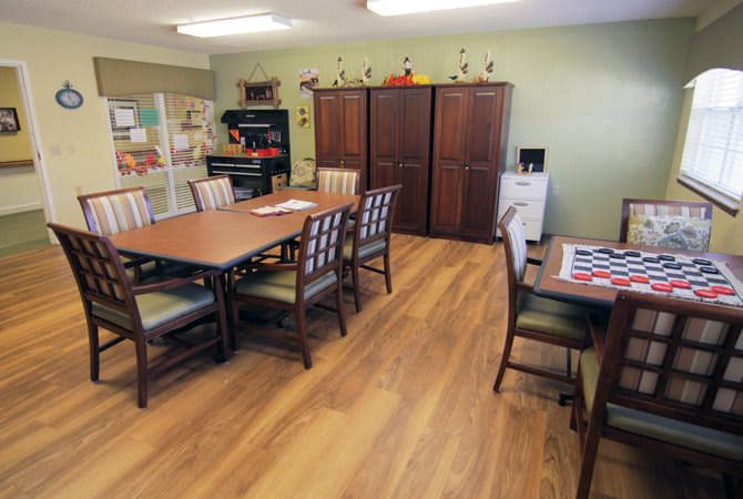 A well-organized dining room with wooden tables, chairs, and cabinets, featuring a cozy interior setting.