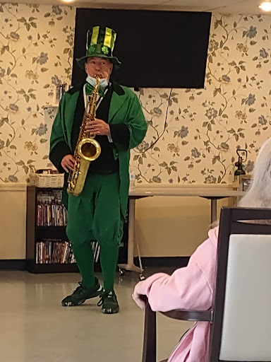 A musician dressed in a vibrant green outfit plays the saxophone for an audience.
