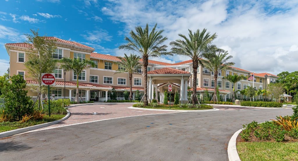 A multi-story residential building with palm trees and a driveway.