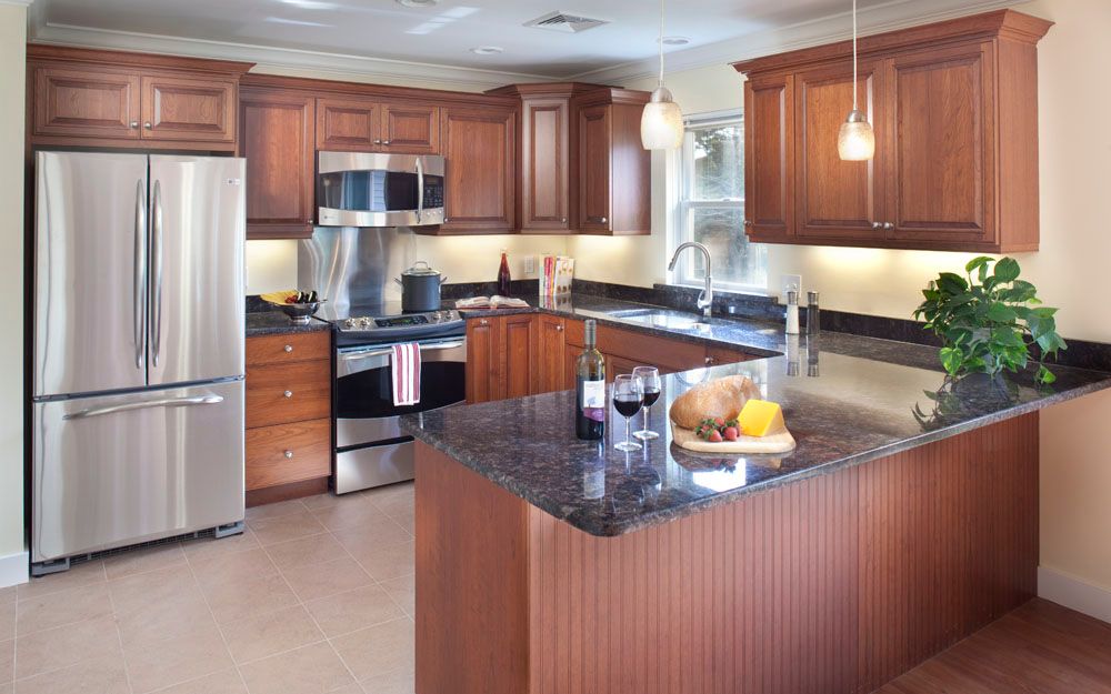 A modern kitchen with wood cabinets, stainless steel appliances, and a granite countertop island.