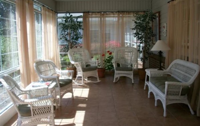 A cozy sunroom with wicker furniture and indoor plants basking in natural light.