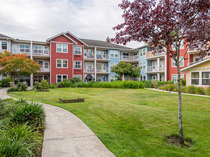 A well-maintained apartment building with a landscaped lawn and walkway.