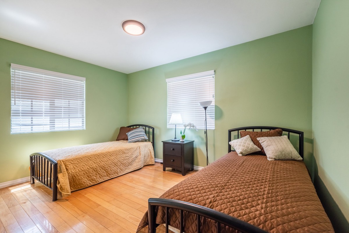 A cozy bedroom with two twin beds, green walls, and wooden flooring.