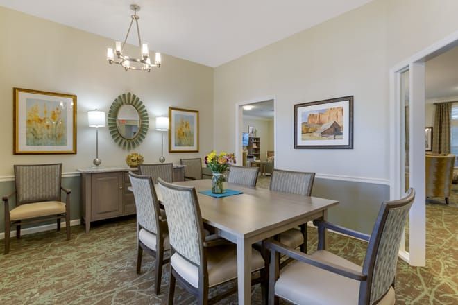 A modern dining room with elegant decor, featuring a chandelier and stylish wall art.
