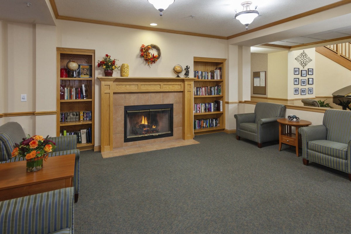 A cozy library space featuring a fireplace surrounded by bookshelves and comfortable seating.
