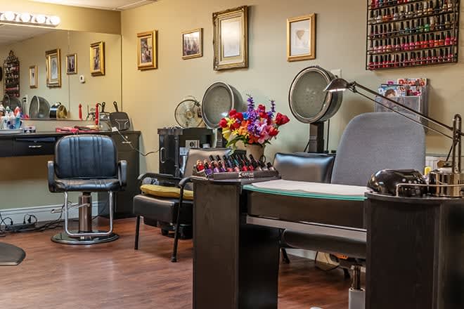 A cozy salon interior featuring chairs, hair dryers, and a vibrant flower arrangement.