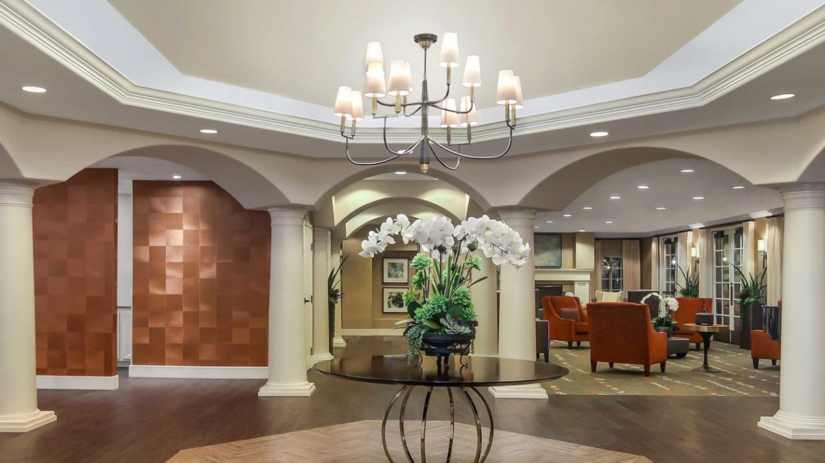 A well-decorated lobby featuring a central table with flowers and a chandelier.