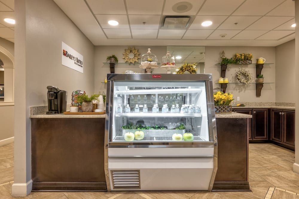 A modern cafe interior featuring a dessert display case surrounded by decorative flowers.