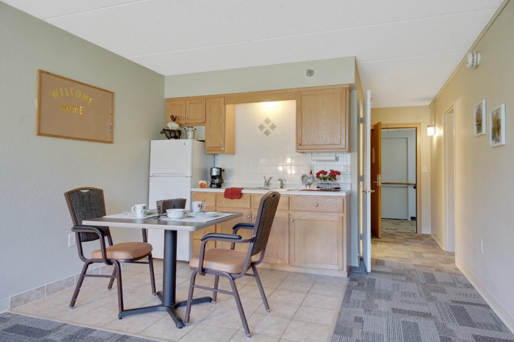 A small apartment kitchen and dining area with a table, chairs, and refrigerator.