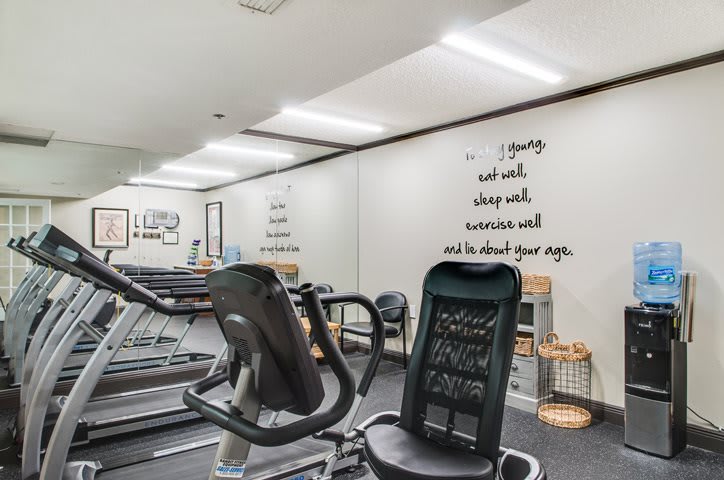 A modern gym with treadmills and motivational quotes on the wall.