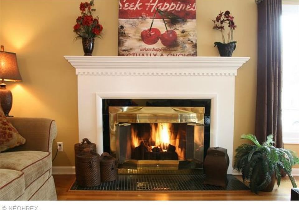 A cozy living room with a lit fireplace and decorative mantel.