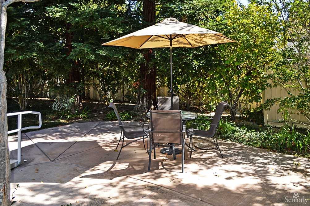 A serene garden patio with an umbrella and furniture set for relaxing.
