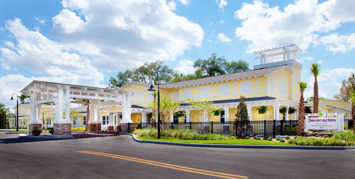 A sunny view of a charming yellow building with a landscaped front yard.