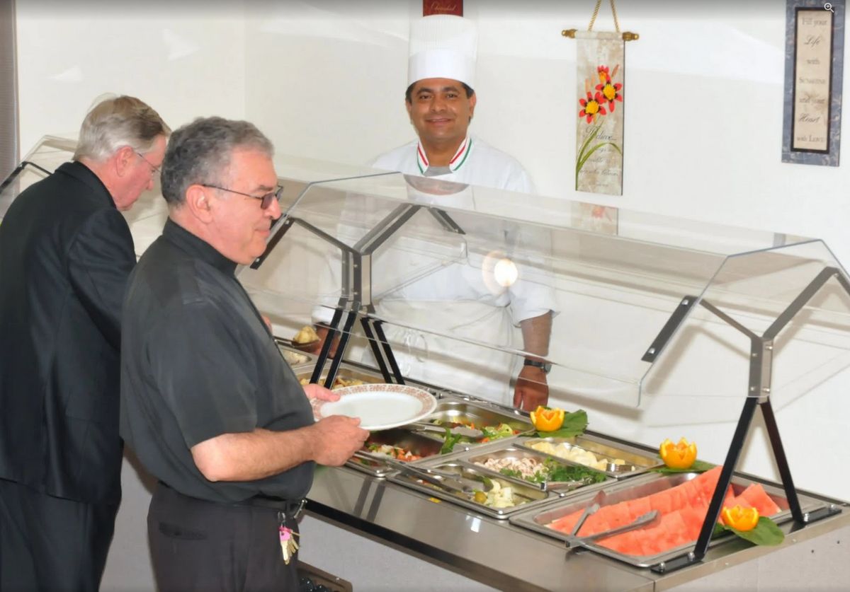 A person serving themselves at a buffet with a chef overseeing the food display.