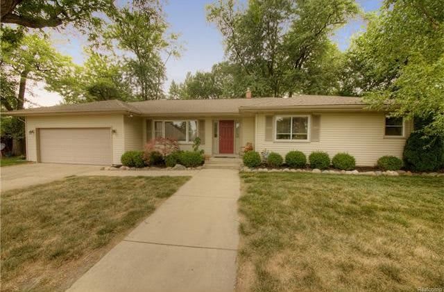 A suburban house with a red door and a well-maintained front yard.