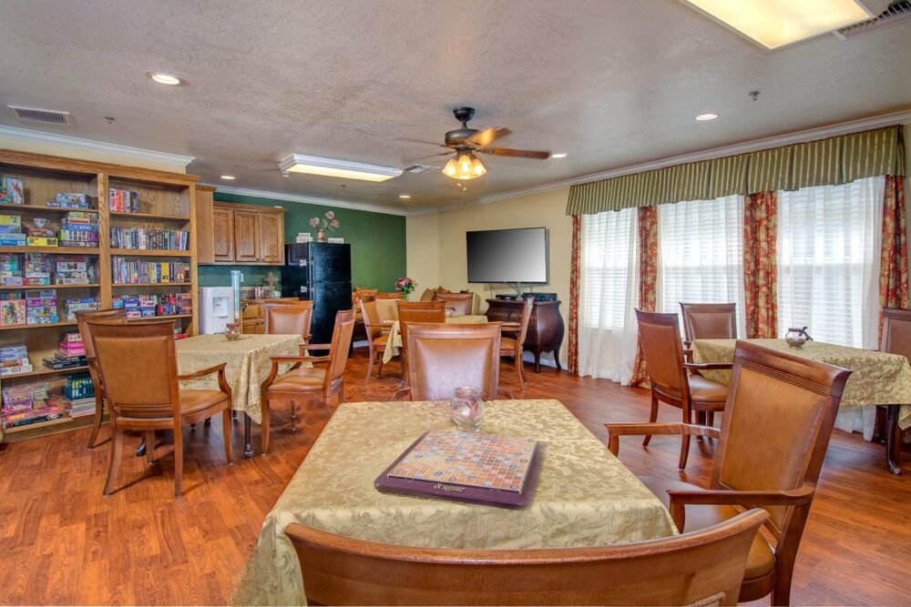 A cozy dining area with wooden tables and chairs, featuring a kitchen in the background.