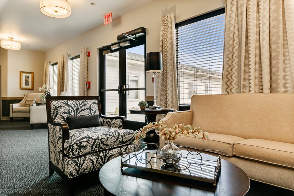 A cozy living room interior with a beige sofa, patterned armchair, and decorative elements.