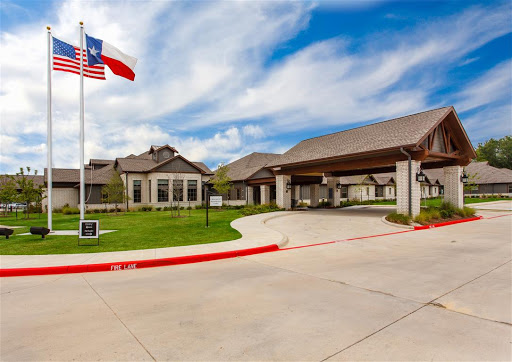 A modern residential building in Texas featuring a flag and a well-maintained driveway under a cloudy sky.