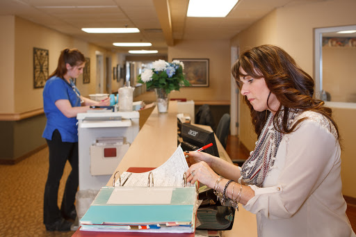 Two staff members working in an office reception area.
