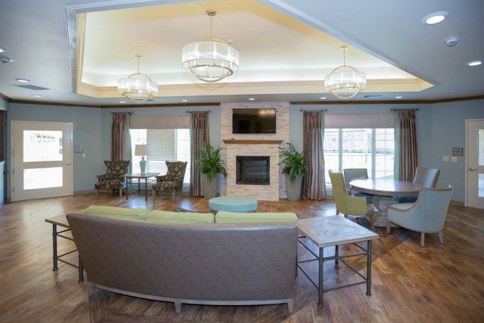 A modern living room with elegant chandeliers, a cozy fireplace, and stylish furnishings.
