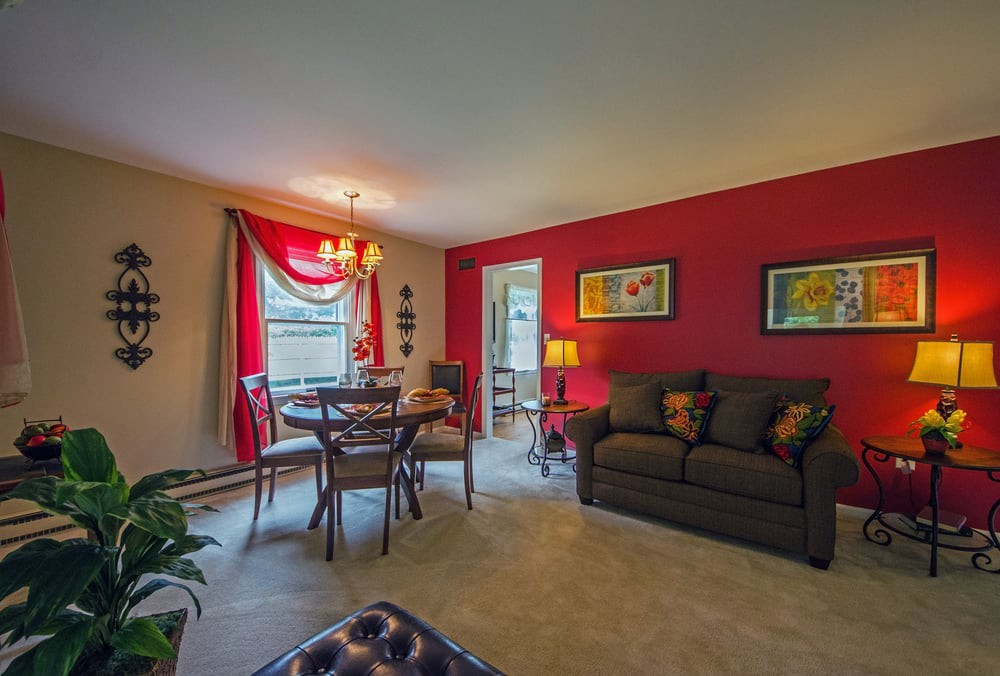 A cozy living and dining area with a red accent wall, featuring a sofa, dining table, and decorative elements.