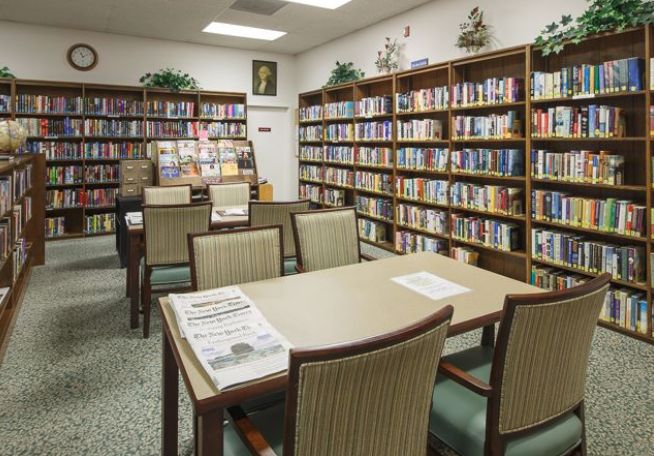 A quiet library with tables and chairs surrounded by bookshelves.