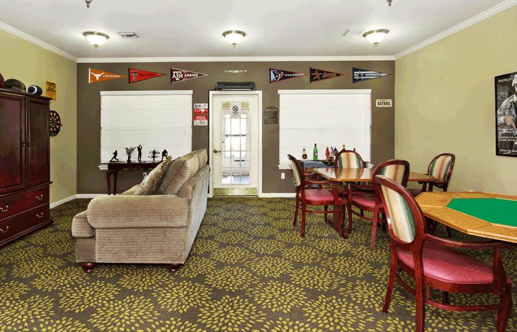 A cozy living room with a sofa, dining table, and chairs, decorated with banners and a patterned carpet.