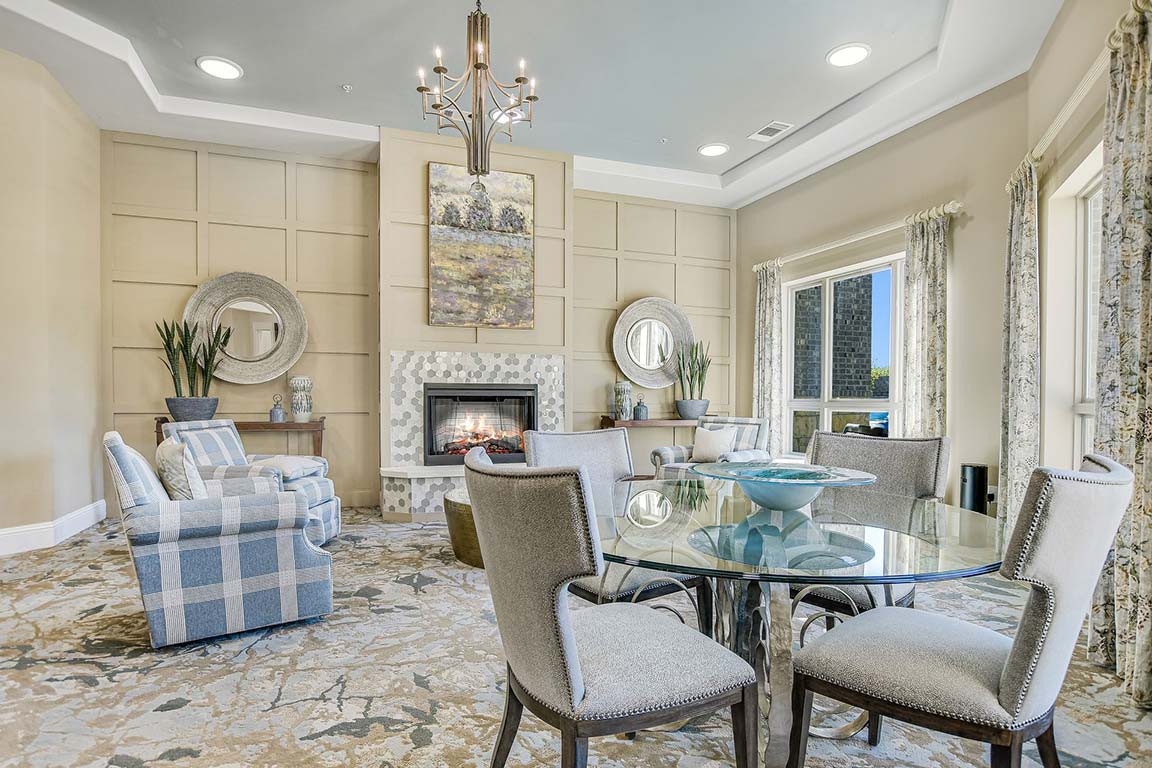 A cozy living room with elegant furnishings, featuring a fireplace and a chandelier.