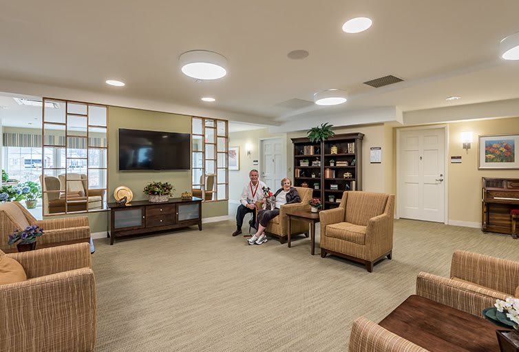 A cozy living room with comfortable seating and a television, featuring individuals enjoying the space.